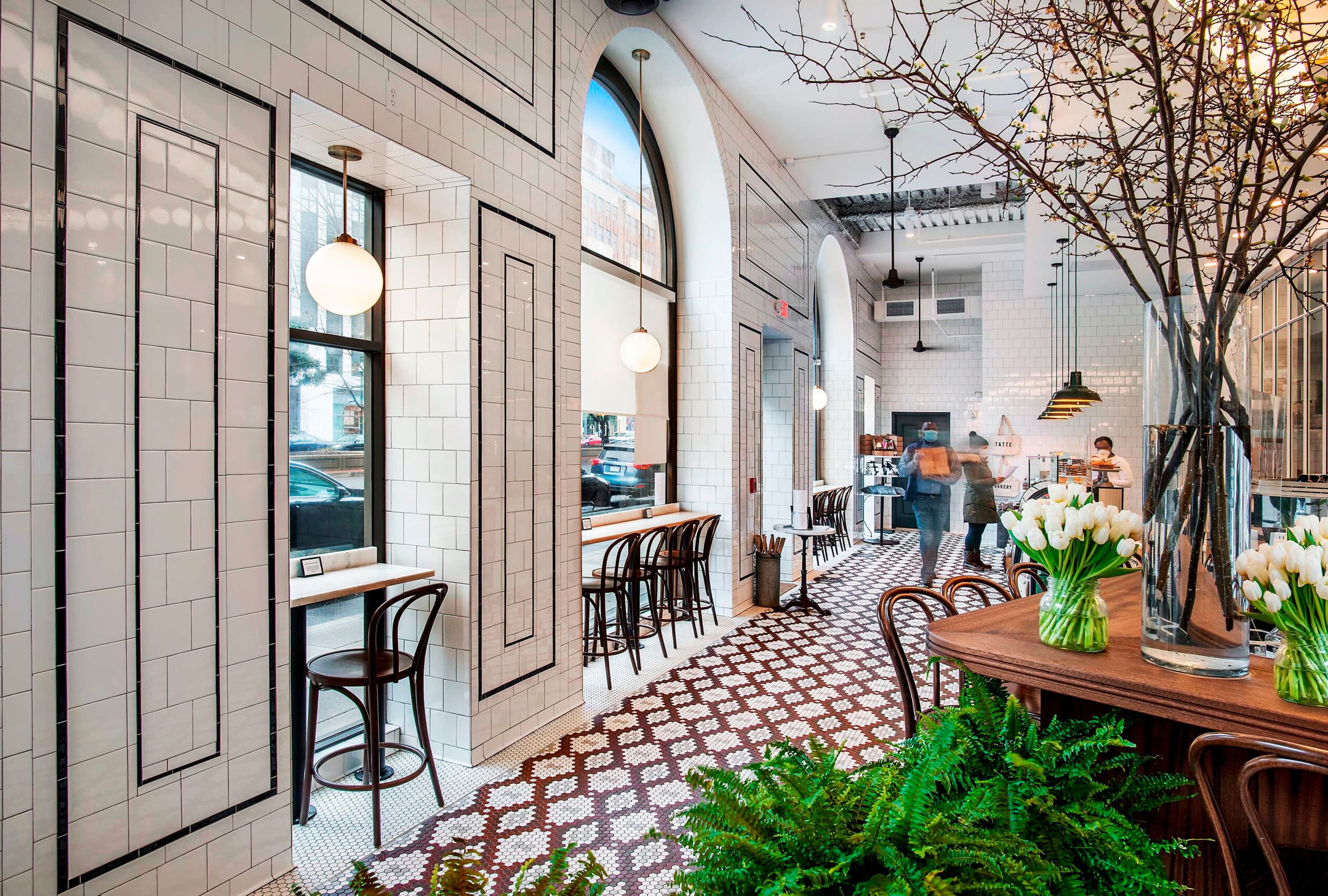 A tiled café interior with bentwood chairs and fresh flowers